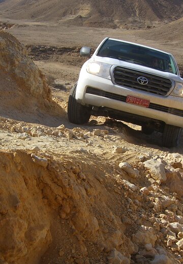 Beim Offroad im Oman muss in den Bergen aufmerksam gefahren werden. | © 4x4 Exploring GmbH Ein Allradfahrzeug passiert ein felsigen Abschnitt der an einem Abgrund vorbei führt. Offroad Oman | © 4x4 Exploring GmbH